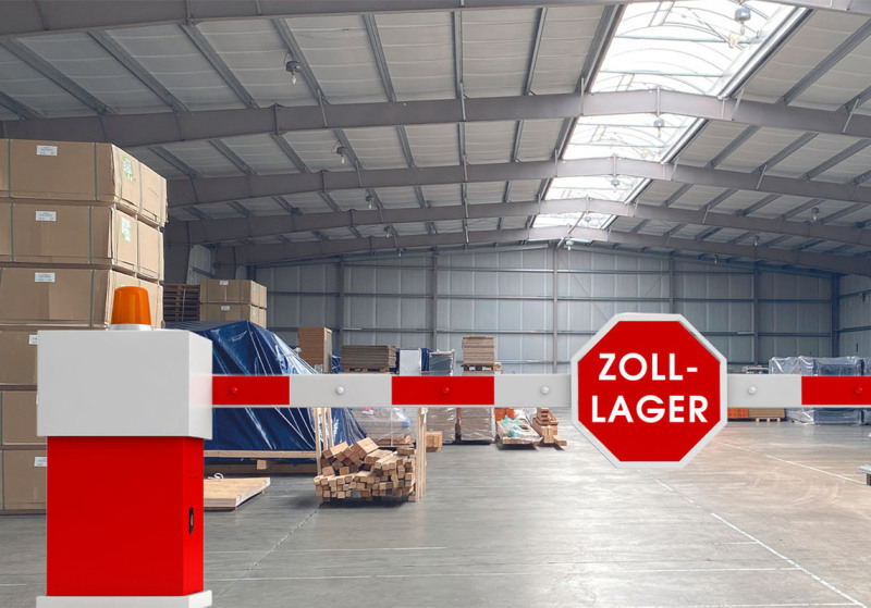 The rear part of a warehouse is separated from the rest by a barrier from the viewer. The barrier is red/white and has a STOP traffic sign. Instead of STOP it says ZOLL-LAGER, which is customs ware house.