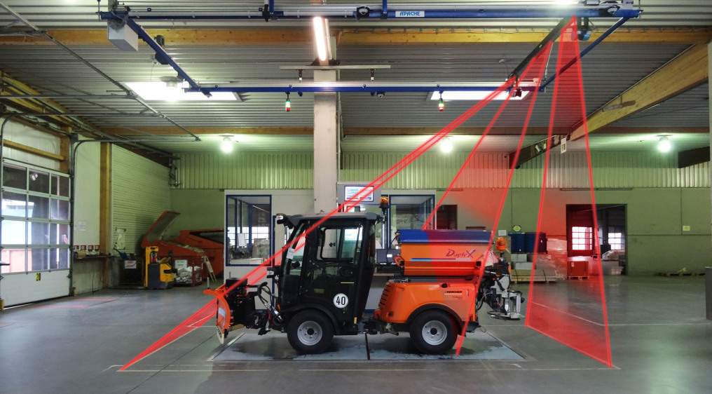 A sweeper, a small vehicle, stands on the weighing surface of the "Apache" weighing and measuring system. Three red laser areas indicate the measurement. Of course, it is a photo monatge,