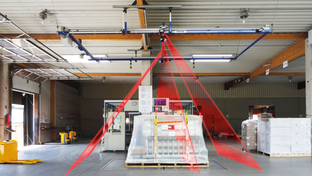 The "Apache" measuring and weighing system is shown. On the measuring surface there is a pallet with goods packed in foil. A red laser is schematically mounted on the right, left and front,