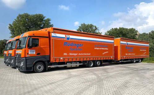 Between two rows of trucks stands a tarpaulin low loader, which you look at from the back. All tarpaulins are open, so that only the skeleton, the linkage is left. At the back, you can drive up on a full back wall.