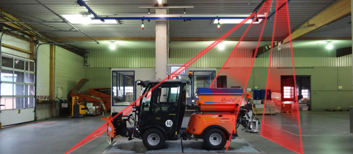 A sweeper, a vehicle, stands on the weighing surface of the measuring and weighing system "Apache". Three symbolized lasers symbolize the measuring of the object.