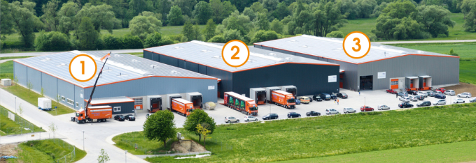 It is a photo taken by a drone. You can see several warehouses. All warehouses of the forwarder are numbered. On the photos there are large numbers in a circle with white area and orange border on the warehouses.